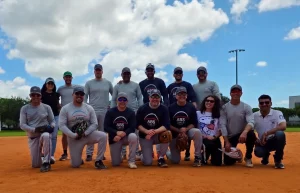 Employees from ABS and ABS Wind Miami, along with their families, gathered on a softball field during a company team-building and family event.