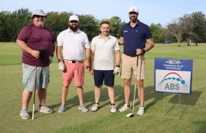 CMC Steel Oklahoma representatives at the CMC Steel Oklahoma Golf Tournament beside an ABS Atlantic Bearingsponsor sign